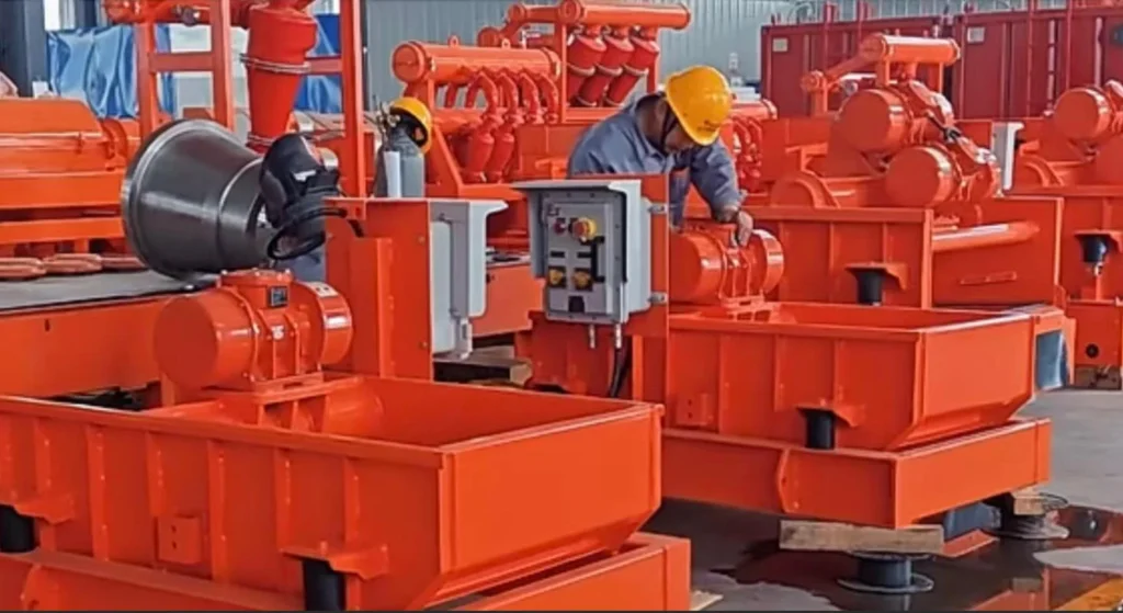 Operário de fábrica usando um capacete de segurança amarelo ajusta equipamentos de máquinas industriais laranja em uma instalação de fabricação.