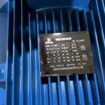 Close-up of an electric motor nameplate on a blue three-phase motor, showing specifications like voltage, capacity, and manufacturer Taizhou Dongchun Motor Co., Ltd.